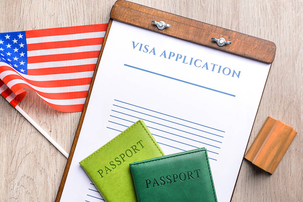 Formulário de pedido de visto, passaportes, carimbo e bandeira dos EUA na mesa. Conceito de imigração
 - Foto, Imagem