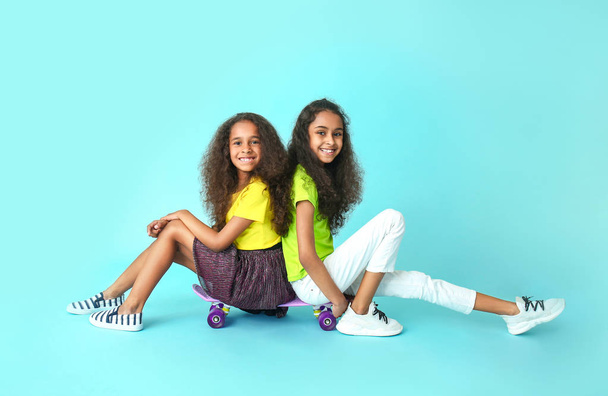Cute African-American girls with skateboards on color background - Foto, Bild