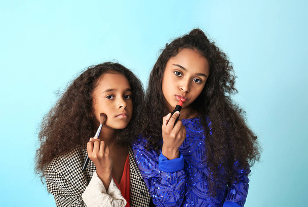 kleine afrikanisch-amerikanische Mädchen beim Make-up auf farbigem Hintergrund - Foto, Bild