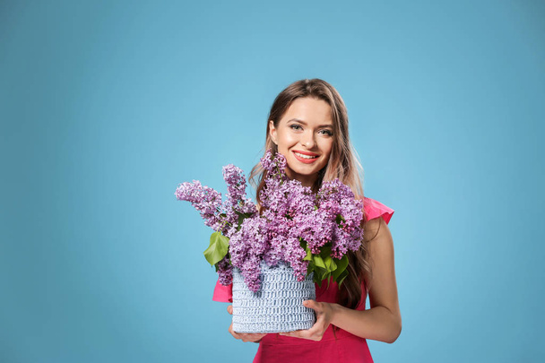 Beautiful young woman with bouquet of lilac flowers on color background - Photo, image