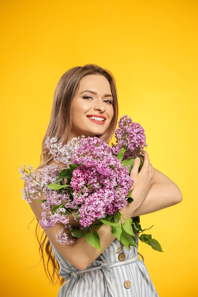 Красивая молодая женщина с букетом лиловых цветов на цветном фоне
 - Фото, изображение