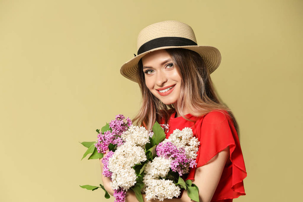 Renkli arka planda leylak çiçek buketi ile güzel genç kadın - Fotoğraf, Görsel