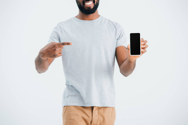 oříznutý pohled afrického amerického muže ukazoval na smartphone s prázdnou obrazovkou, izolovaný na šedé - Fotografie, Obrázek