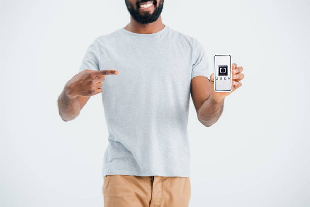 KYIV, UCRANIA - 17 de mayo de 2019: vista recortada del hombre afroamericano apuntando al teléfono inteligente con la aplicación uber, aislado en gris
  - Foto, Imagen