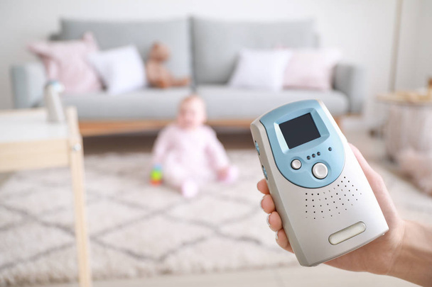 Female hand with modern baby monitor and little child on background - Foto, imagen