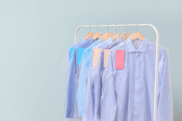 Rack with clothes after dry-cleaning on light background - Photo, image