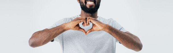 vista ritagliata di felice uomo africano americano in t-shirt grigia mostrando il segno del cuore isolato sul grigio
 - Foto, immagini