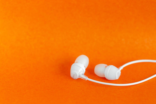 White earbuds on orange colorful background with copy space for text - Photo, Image