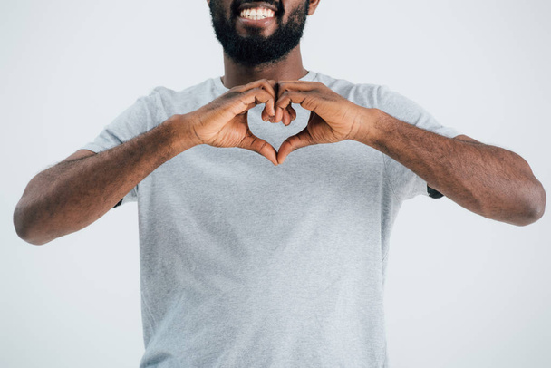 vue recadrée d'un homme afro-américain souriant en t-shirt gris montrant un signe cardiaque isolé sur gris
 - Photo, image