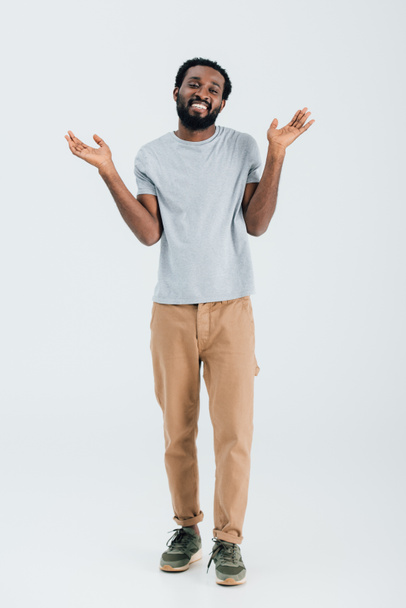 happy african american man in grey t-shirt gesturing isolated on grey - Фото, изображение