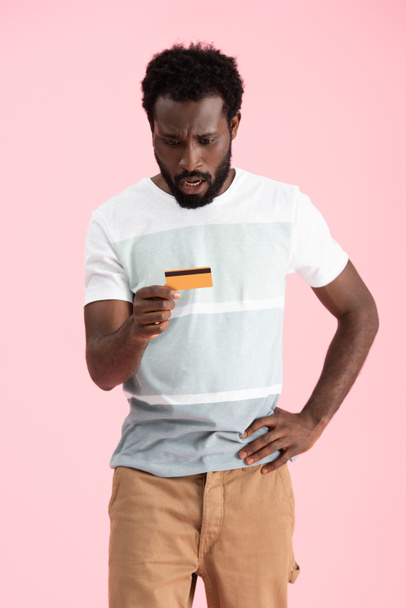 järkyttynyt afrikkalainen amerikkalainen mies osoittaa luottokortti eristetty vaaleanpunainen
 - Valokuva, kuva