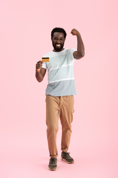 succès homme afro-américain montrant carte de crédit isolé sur rose
 - Photo, image