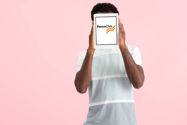 KYIV, UCRAINA - 17 MAGGIO 2019: uomo afroamericano che grida e mostra tablet digitale con app per club forex, isolato su rosa
 - Foto, immagini