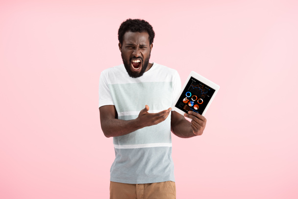 emotionele Afro-Amerikaanse man schreeuwen en tonen digitale tablet met infographic, geïsoleerd op roze - Foto, afbeelding