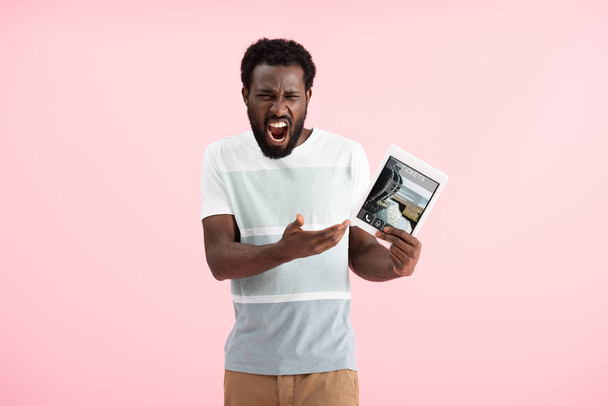emotional african american man screaming and showing digital tablet with tickets app, isolated on pink - Photo, Image