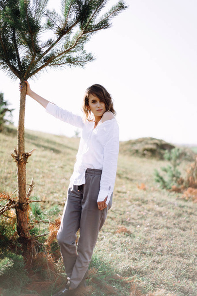 Volledige lengte weergave van vrouwelijke model poseren in het veld met bomen - Foto, afbeelding