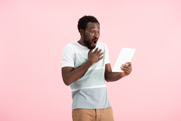 schockierter Afroamerikaner mit Videochat auf digitalem Tablet isoliert auf rosa - Foto, Bild