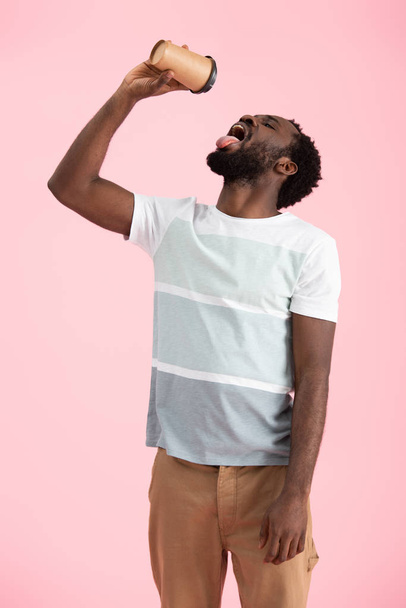 bearded african american man drinking coffee to go, isolated on pink - Photo, Image