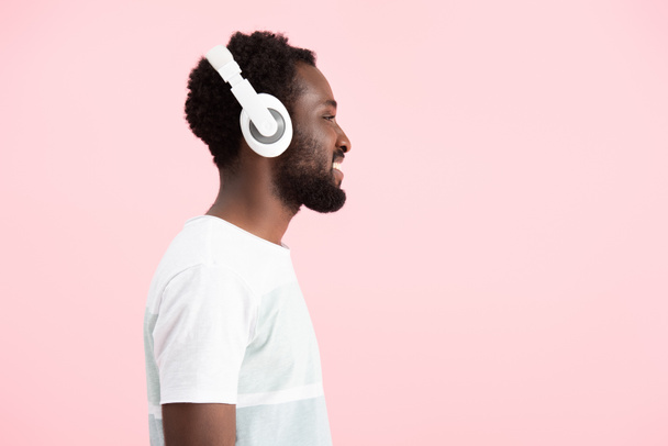 bearded african american man listening music with headphones, isolated on pink - Photo, Image