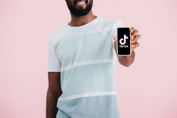KYIV, UCRANIA - 17 de mayo de 2019: vista recortada del hombre afroamericano mostrando su teléfono inteligente con la aplicación Tik Tok, aislado en rosa
  - Foto, imagen