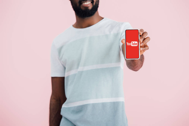 KYIV, UCRANIA - 17 de mayo de 2019: vista recortada del hombre afroamericano que muestra el teléfono inteligente con la aplicación de youtube, aislado en rosa
  - Foto, imagen