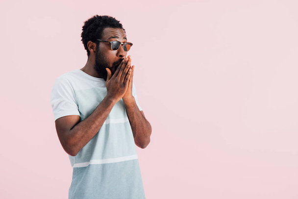junge überraschte Afroamerikaner von Mann mit Sonnenbrille, isoliert auf rosa - Foto, Bild