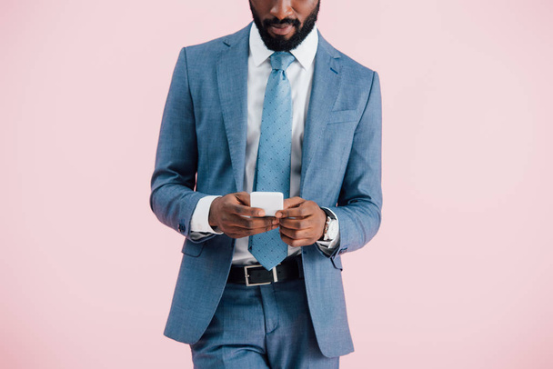 cropped view of african american businessman using smartphone, isolated on pink   - Fotoğraf, Görsel