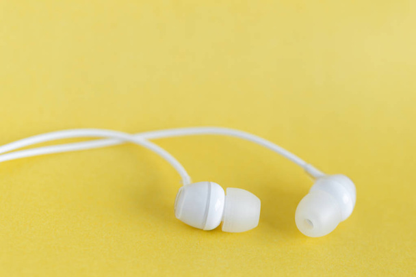 Λευκά ακουστικά σε κίτρινο παστέλ φόντο με χώρο αντιγραφής για κείμενο - Φωτογραφία, εικόνα