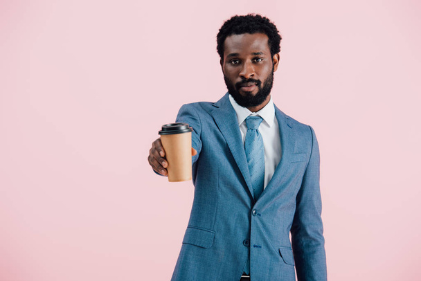 serious african american businessman holding coffee to go, isolated on pink - Foto, Imagem