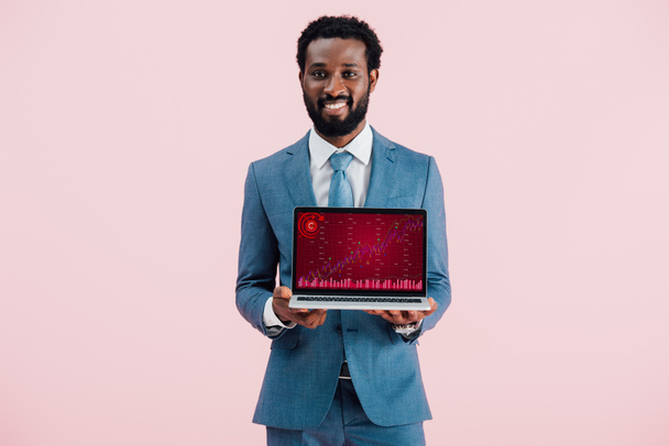 uomo d'affari afroamericano sorridente mostrando laptop con grafico isolato su blu
 - Foto, immagini