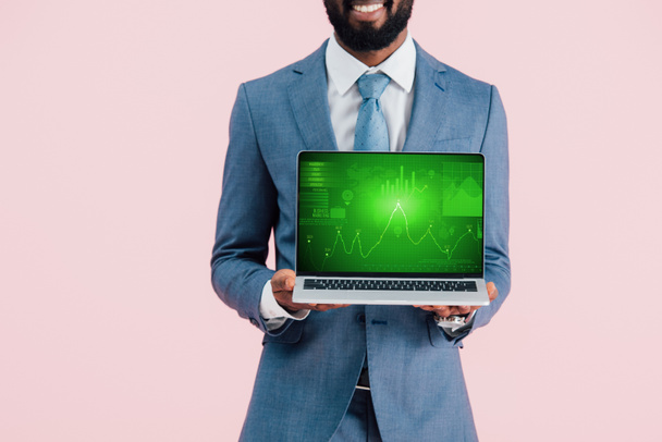 περικομμένη όψη του χαμογελαστή Αφρικανού Αμερικανού επιχειρηματία που δείχνει φορητό υπολογιστή με γράφημα απομονωμένη στο μπλε - Φωτογραφία, εικόνα