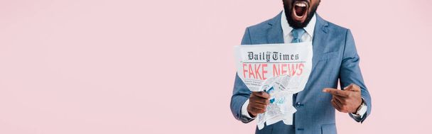 przycięte widok zły African American biznesmen krzyczeć i czytanie gazety z fałszywych wiadomości na białym tle na różowy - Zdjęcie, obraz