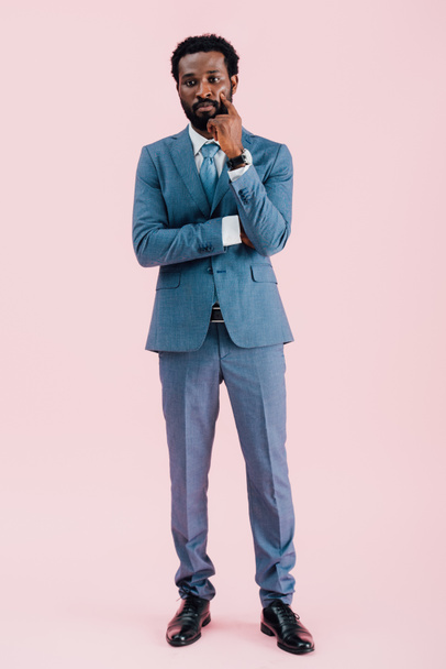thoughtful african american businessman in suit, isolated on pink - Fotó, kép