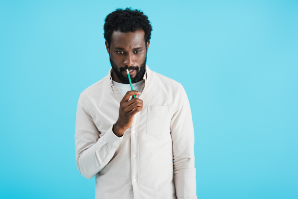 nachdenklicher afrikanisch-amerikanischer Mann mit Bleistift isoliert auf blau - Foto, Bild