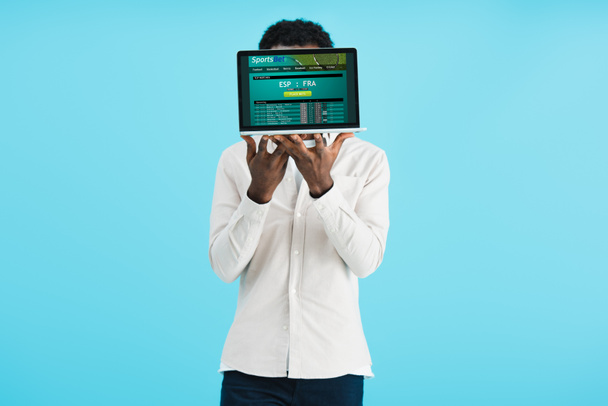 uomo afroamericano mostrando laptop con scommesse sportive sito web isolato su blu
 - Foto, immagini