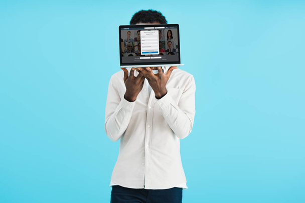 KYIV, UKRAINE - MAY 17, 2019: african american man showing laptop with linkedin  website, isolated on blue - Photo, Image