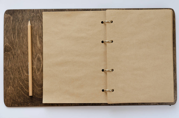 木製のカバーと白い背景に鉛筆とクラフトメモ帳を開きます。テキスト用のスペースを含むモックアップ - 写真・画像