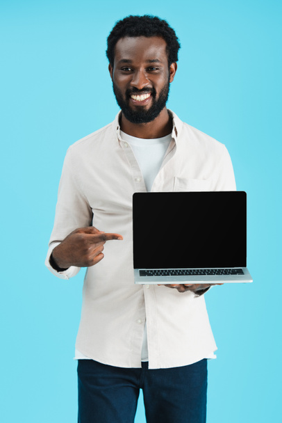 smiling african american man pointing at laptop with blank screen isolated on blue - Valokuva, kuva