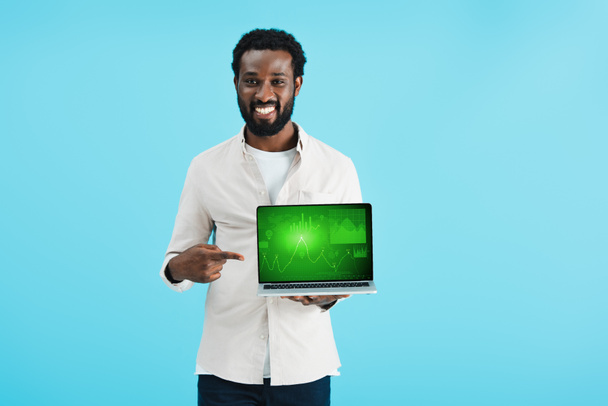 uśmiechnięty African American Man wskazując na laptopie z wykresu izolowane na niebiesko - Zdjęcie, obraz