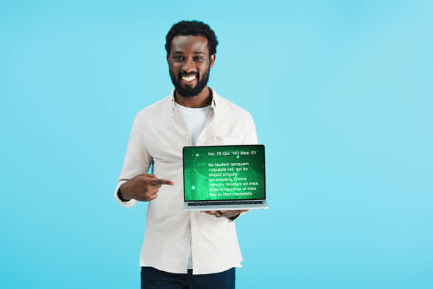 lächelnder afrikanisch-amerikanischer Mann zeigt auf Laptop mit Webseite isoliert auf blau - Foto, Bild