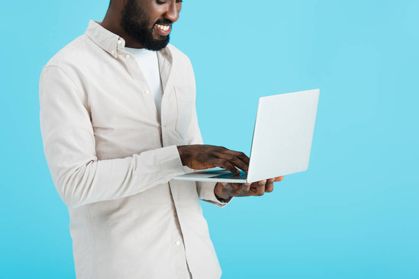 smiling african american man using laptop isolated on blue - Φωτογραφία, εικόνα