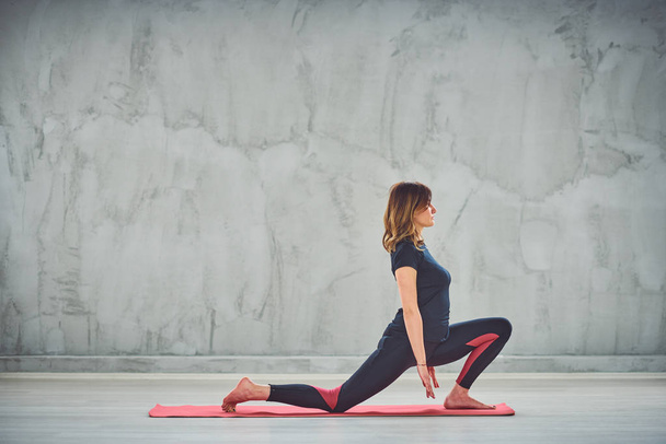 Jeune femme mince faisant fente sur la posture de yoga du genou
. - Photo, image