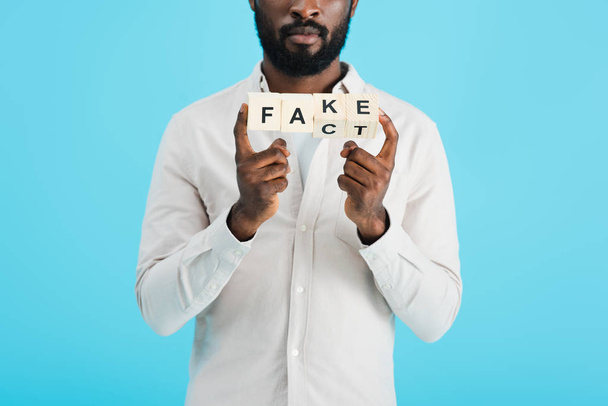 vista cortada do homem americano africano que prende blocos do alfabeto com a palavra do fato, isolada no azul
 - Foto, Imagem
