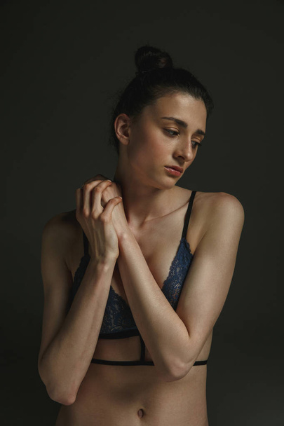 Half-length portrait of young sad woman on dark studio background - Photo, Image