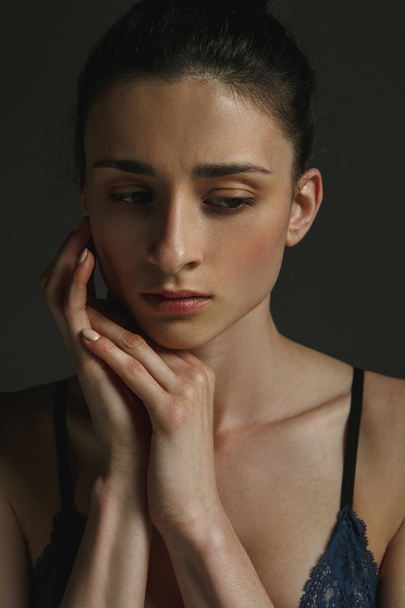 Half-length portrait of young sad woman on dark studio background - Φωτογραφία, εικόνα