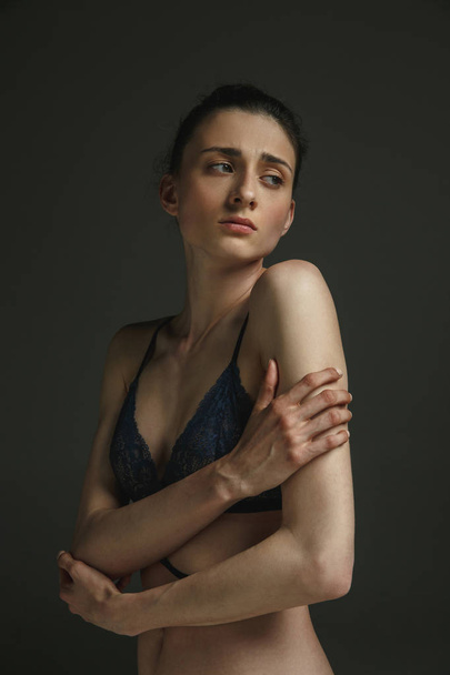 Half-length portrait of young sad woman on dark studio background - Fotografie, Obrázek