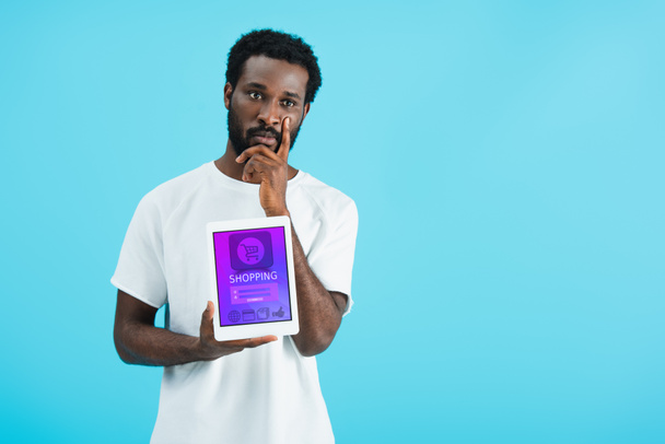hombre afroamericano reflexivo mostrando tableta digital con aplicación de compras, aislado en azul
 - Foto, Imagen