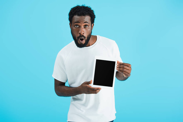 wstrząśnięty African American Man pokazując cyfrowy tablet z pustym ekranem na białym tle na niebiesko  - Zdjęcie, obraz