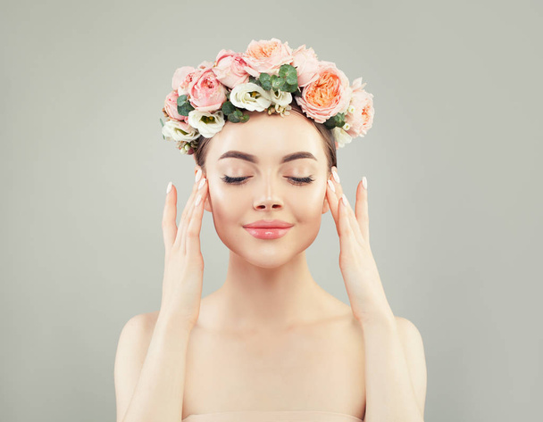 Όμορφη γυναίκα με λουλούδια και καθαρό δέρμα σε γκρι φόντο - Φωτογραφία, εικόνα