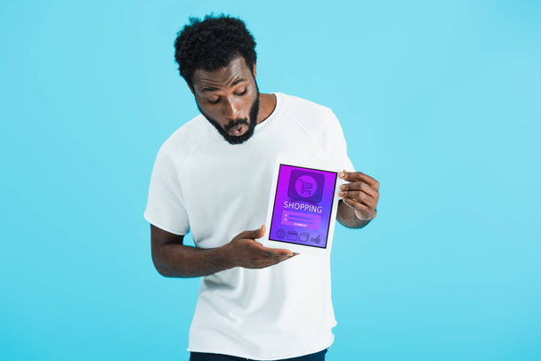 chocado homem americano africano mostrando tablet digital com aplicativo de compras, isolado em azul
 - Foto, Imagem